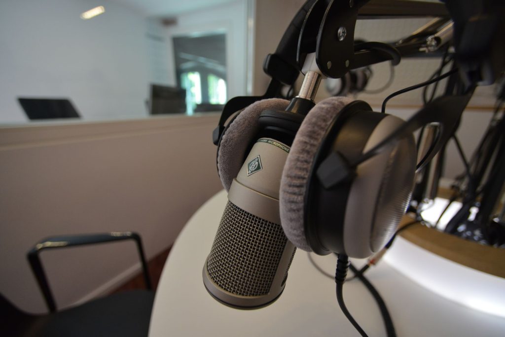 Close-up of a studio microphone with headphones in a recording setting, emphasizing audio quality.