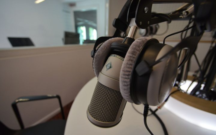 Close-up of a studio microphone with headphones in a recording setting, emphasizing audio quality.