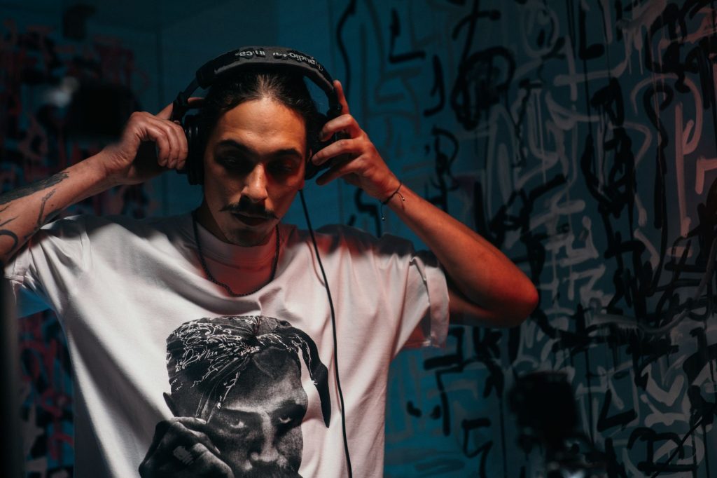 A man wearing headphones in a graffiti-covered room in Lwiw, Ukraine, creating a moody DJ portrait.