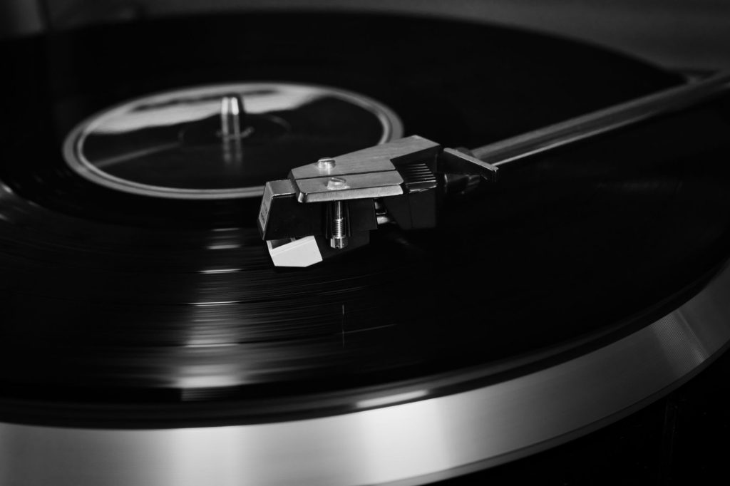 A detailed close-up of a vintage record player playing a vinyl record in black and white.