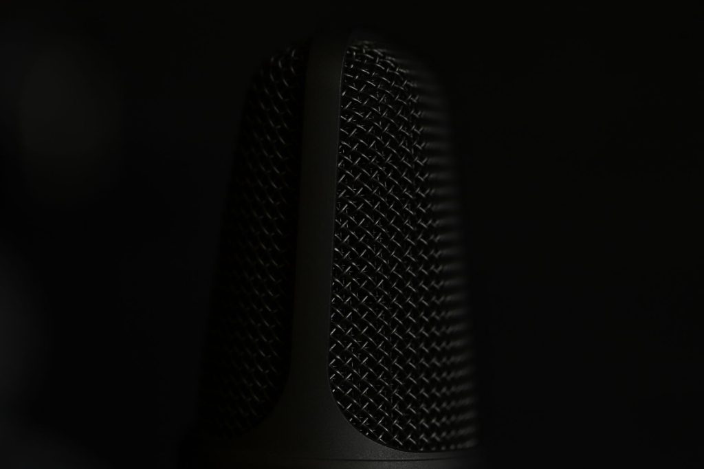 A detailed macro shot of a microphone in a studio setting with a dark background.