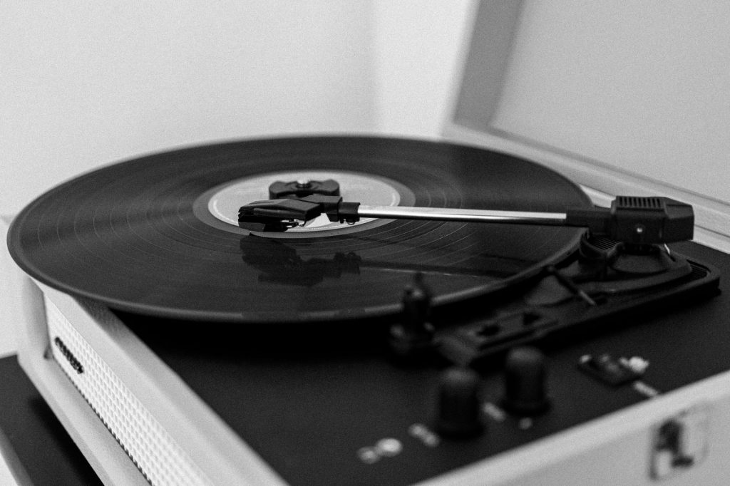 A monochrome photo of a vintage record player with a spinning vinyl record.