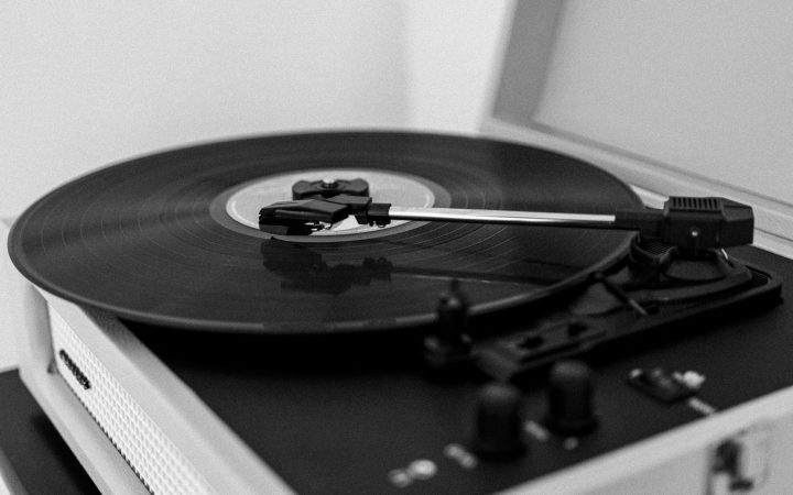 A monochrome photo of a vintage record player with a spinning vinyl record.