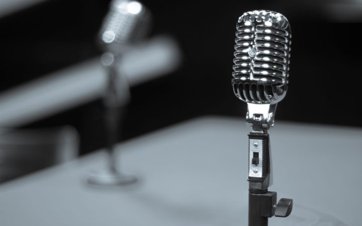 A close-up of a vintage microphone on a stand, perfect for studio recording themes.