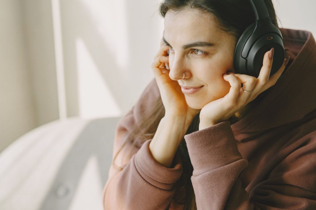 Portrait of a woman relaxing and enjoying music with wireless headphones indoors.