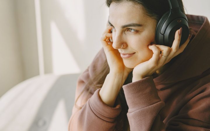 Portrait of a woman relaxing and enjoying music with wireless headphones indoors.