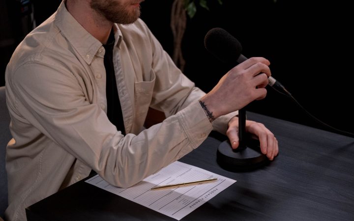 A man prepares for a podcast in a studio with a microphone and notes.