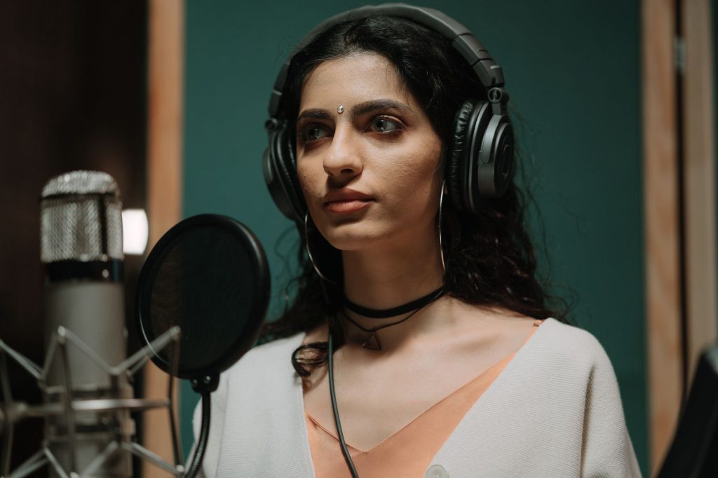 Female singer recording vocals in a professional music studio wearing headphones.