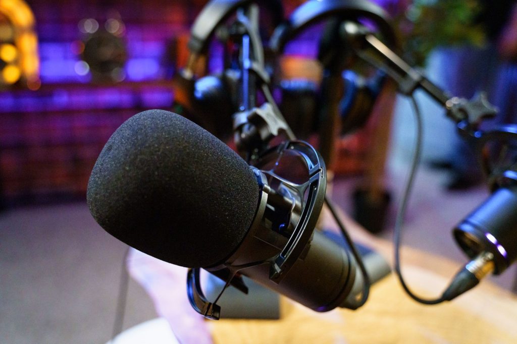 Close-up of studio microphones in a podcast setup with vibrant lighting.