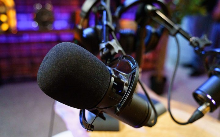 Close-up of studio microphones in a podcast setup with vibrant lighting.