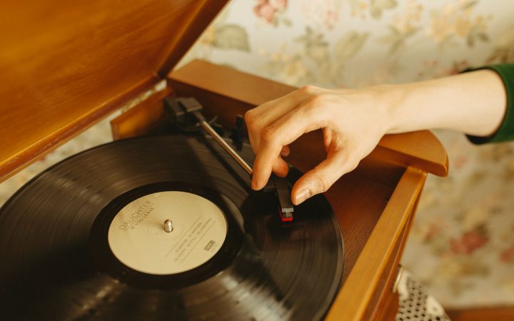 A hand adjusts a needle on a turntable with a retro vinyl record. Nostalgic and vintage vibe.