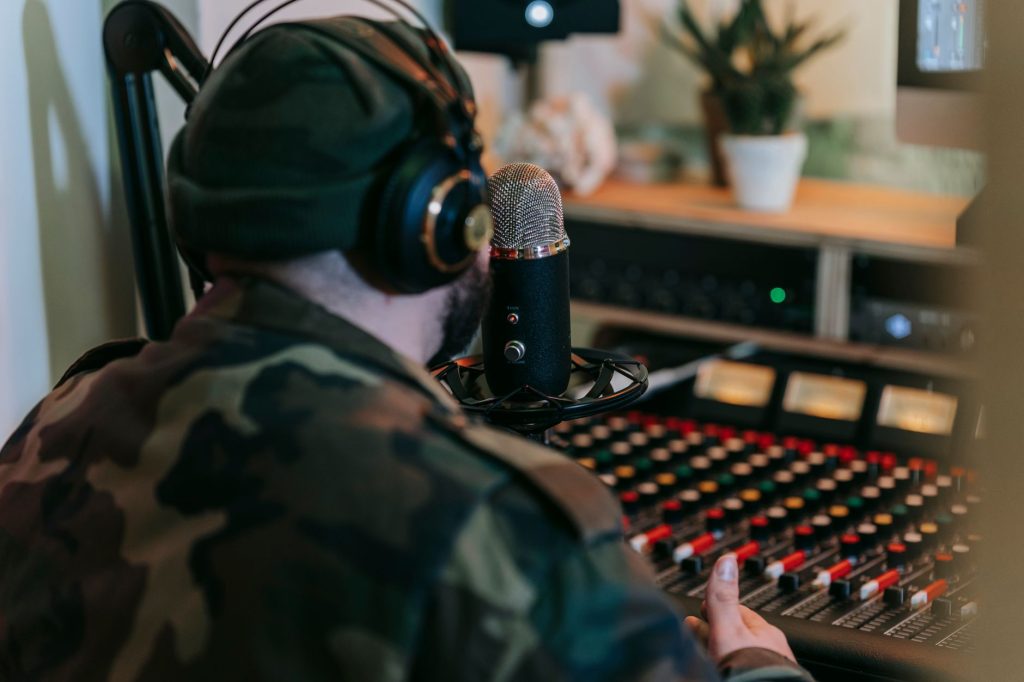Musician recording sound in studio with headphones and mixer, focused on creative audio production.