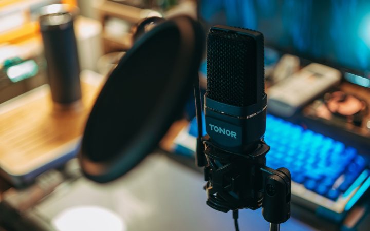 Close-up of a modern studio microphone with pop filter on a desk, perfect for recording.
