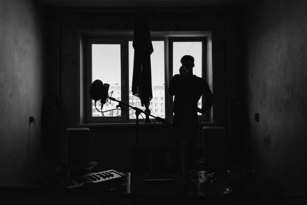 A silhouetted man stands by a window in a monochrome creative studio, capturing a moody ambiance.