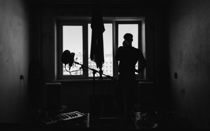 A silhouetted man stands by a window in a monochrome creative studio, capturing a moody ambiance.