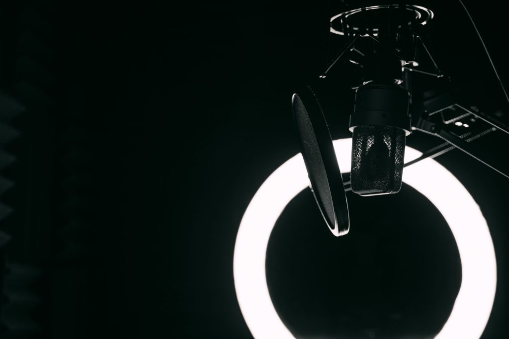 A close-up view of a microphone and ring light in a professional recording studio setting.