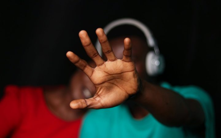 Close-up of a young couple with a hand gesture and headphones, expressing emotion indoors.