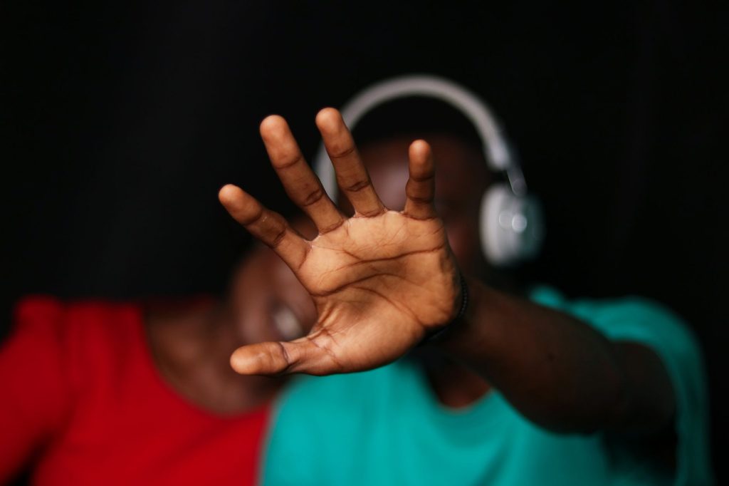 Close-up of a young couple with a hand gesture and headphones, expressing emotion indoors.