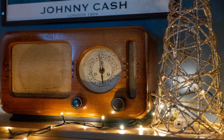 A classic wooden radio adorned with decorative string lights and a retro poster backdrop.