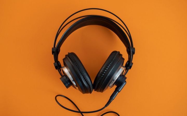 Top view of modern black headphones elegantly posed on a vibrant orange surface.