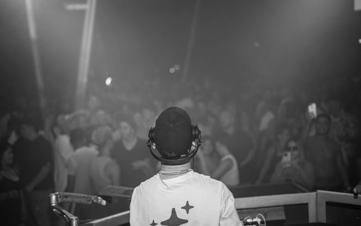 A DJ playing music in front of a vibrant crowd at a night concert.