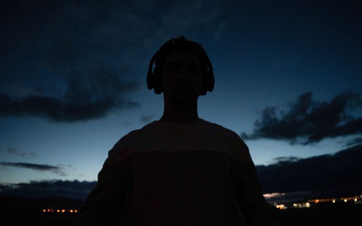 Silhouette of an individual wearing headphones against a twilight sky, capturing serene ambiance.