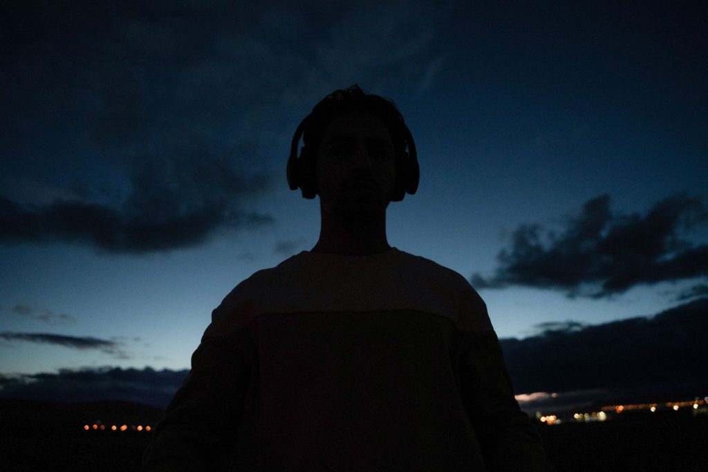 Silhouette of an individual wearing headphones against a twilight sky, capturing serene ambiance.