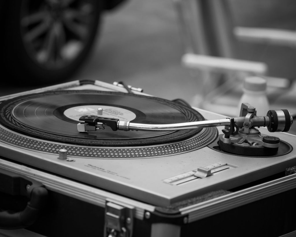 Black and white image of a classic turntable playing a vinyl record, emphasizing retro music.