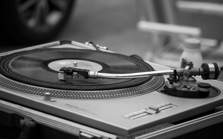 Black and white image of a classic turntable playing a vinyl record, emphasizing retro music.