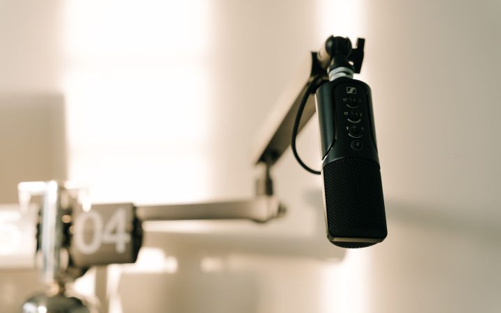 A sleek professional microphone on a boom arm in a minimalist studio.