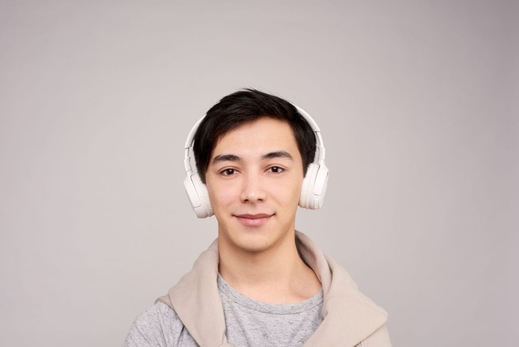 Portrait of a smiling young adult wearing headphones, enjoying music in a relaxed setting.