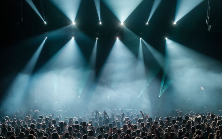 A dynamic concert scene with a large crowd enjoying vibrant stage lighting and a lively atmosphere.