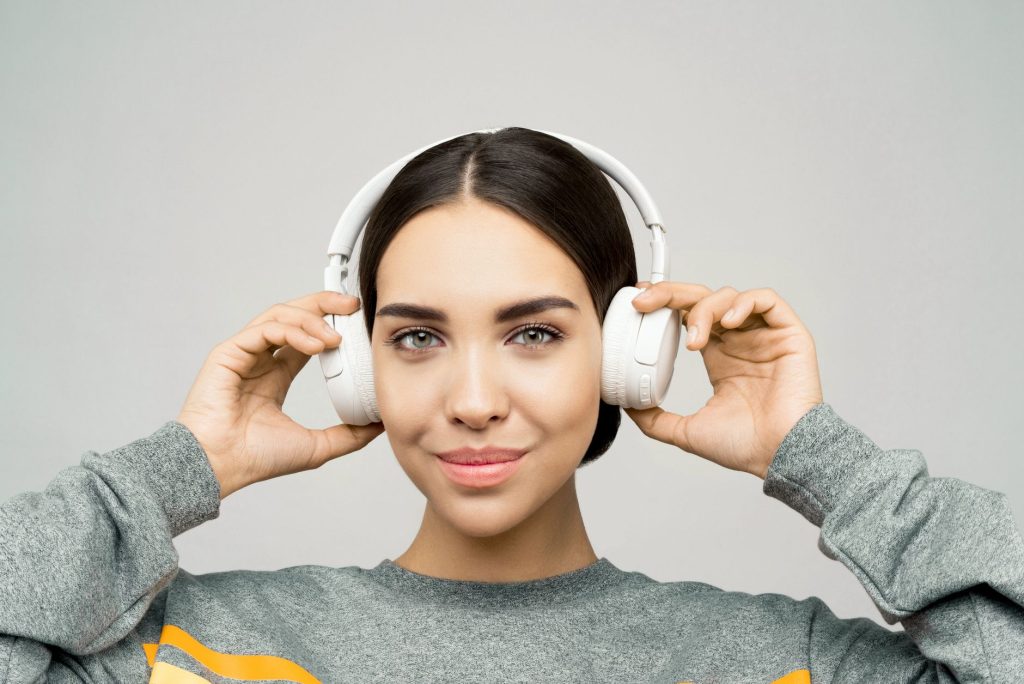 Young woman smiling while listening to music on headphones, creating a relaxed and joyful atmosphere.