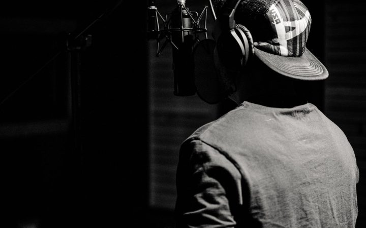 A male singer recording music in a studio, captured in a black and white style.