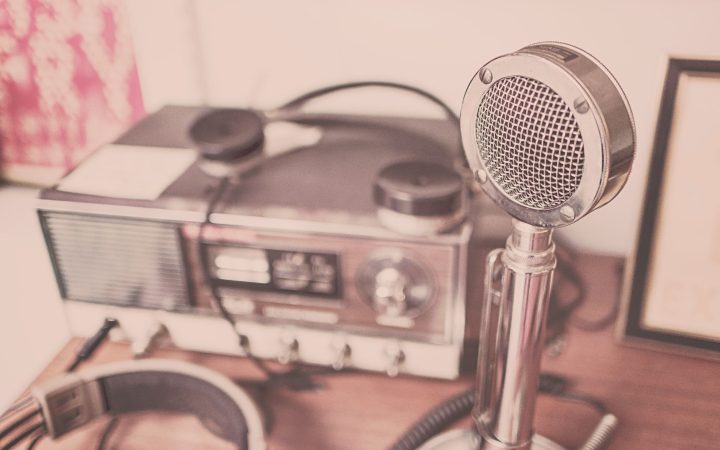 A classic vintage microphone and radio set with headphones displayed on a wooden table.