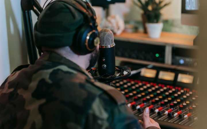 Musician recording sound in studio with headphones and mixer, focused on creative audio production.