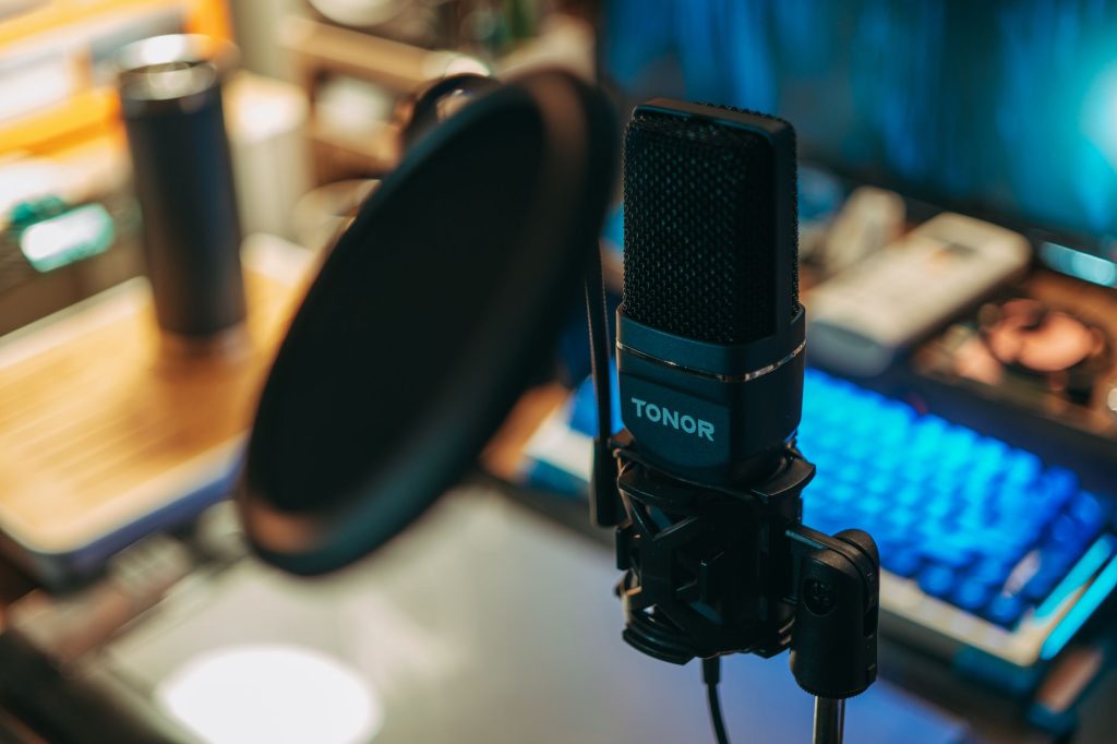 Close-up of a modern studio microphone with pop filter on a desk, perfect for recording.